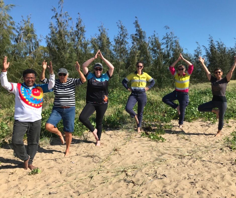 People performing yoga poses on beach.