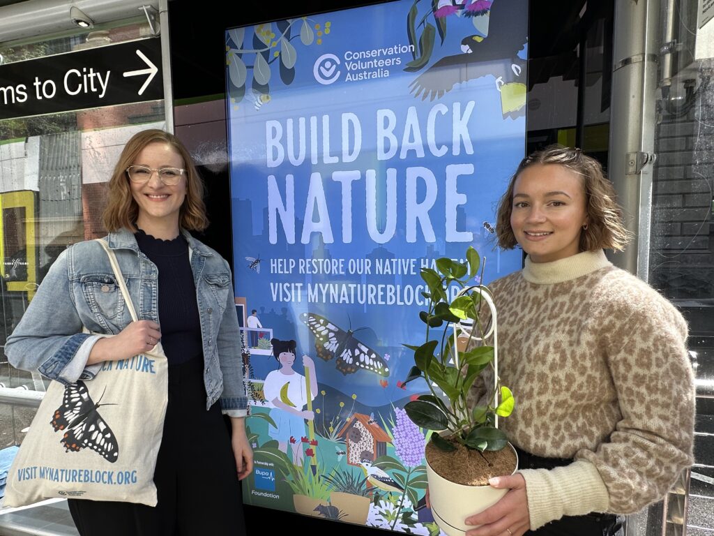 Two people stand in front of a billboard displaying information about Nature Blocks™